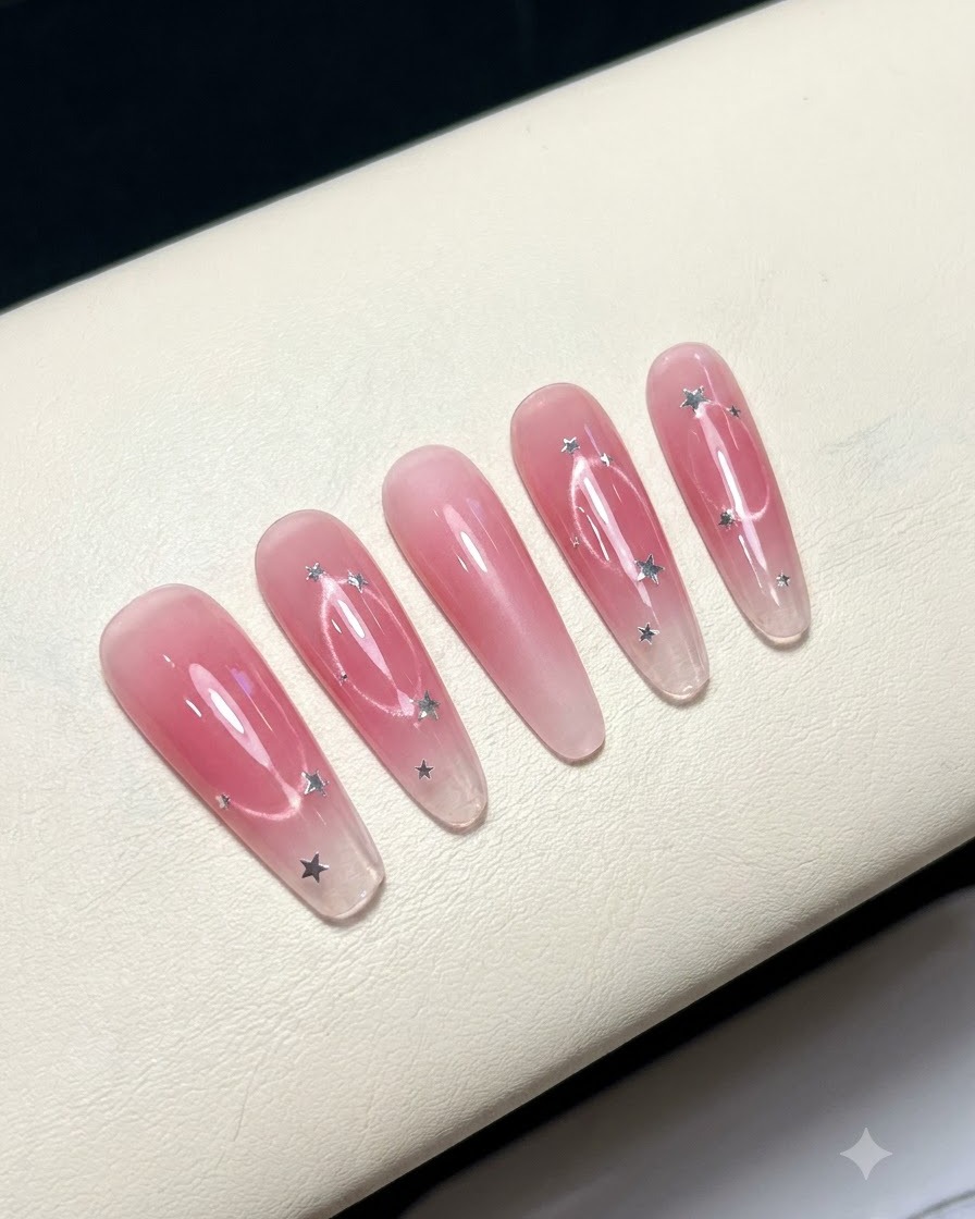 Five false nails arranged on a white surface displaying a pink blush center design.