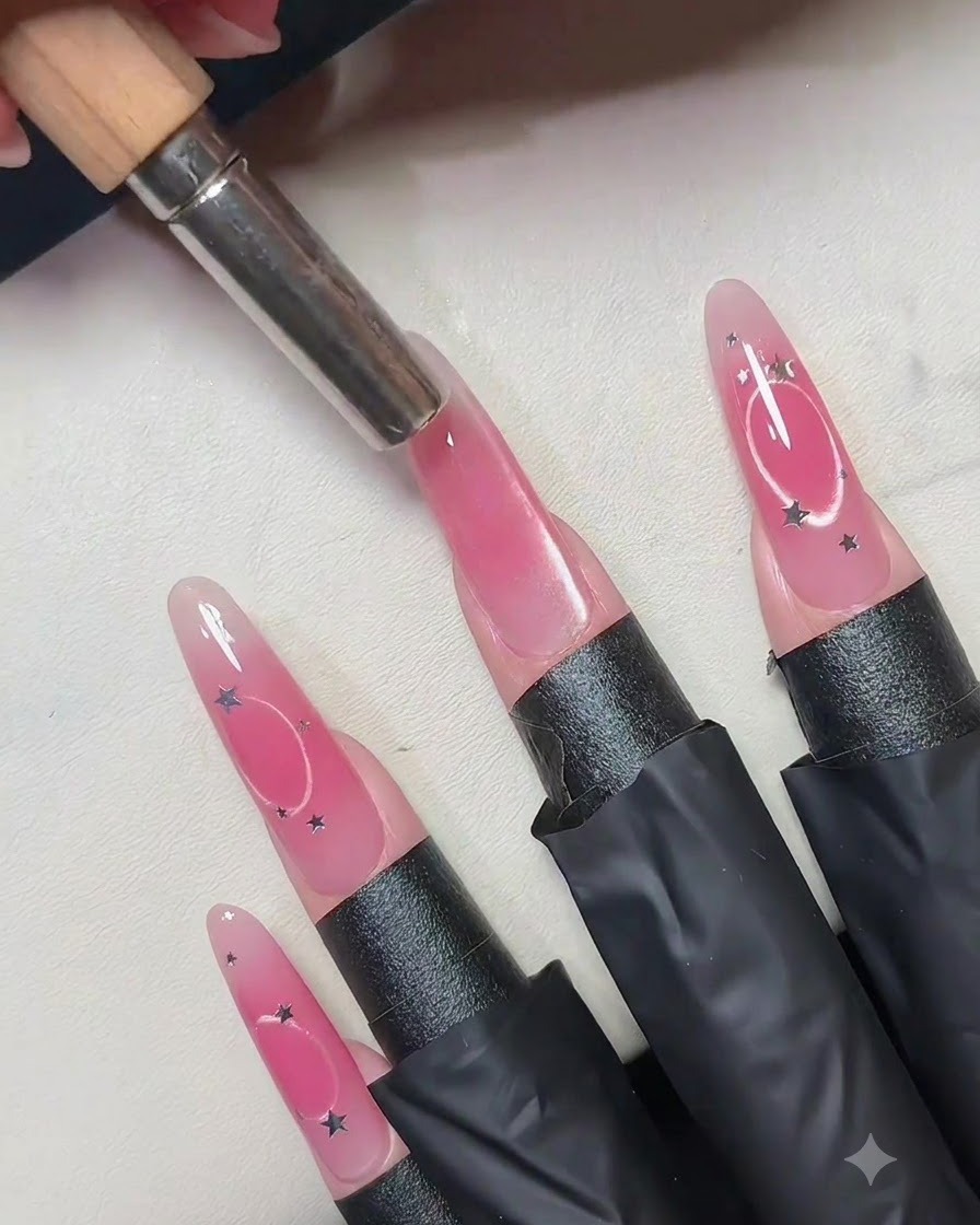 A cylindrical magnet held vertically above the center of a pink cat eye gel nail.