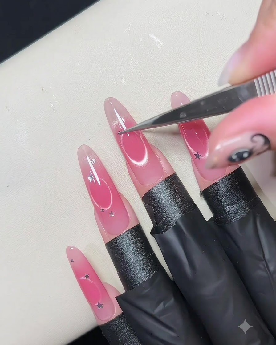 Fine tweezers placing small silver star sequins around the edge of a hollow circular nail design.