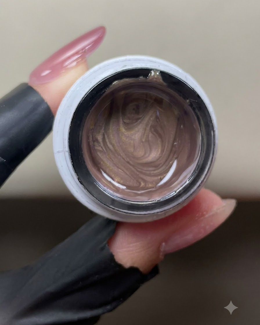 An open jar of shimmer pink-gold cat-eye gel showing swirling metallic magnetic particles inside.