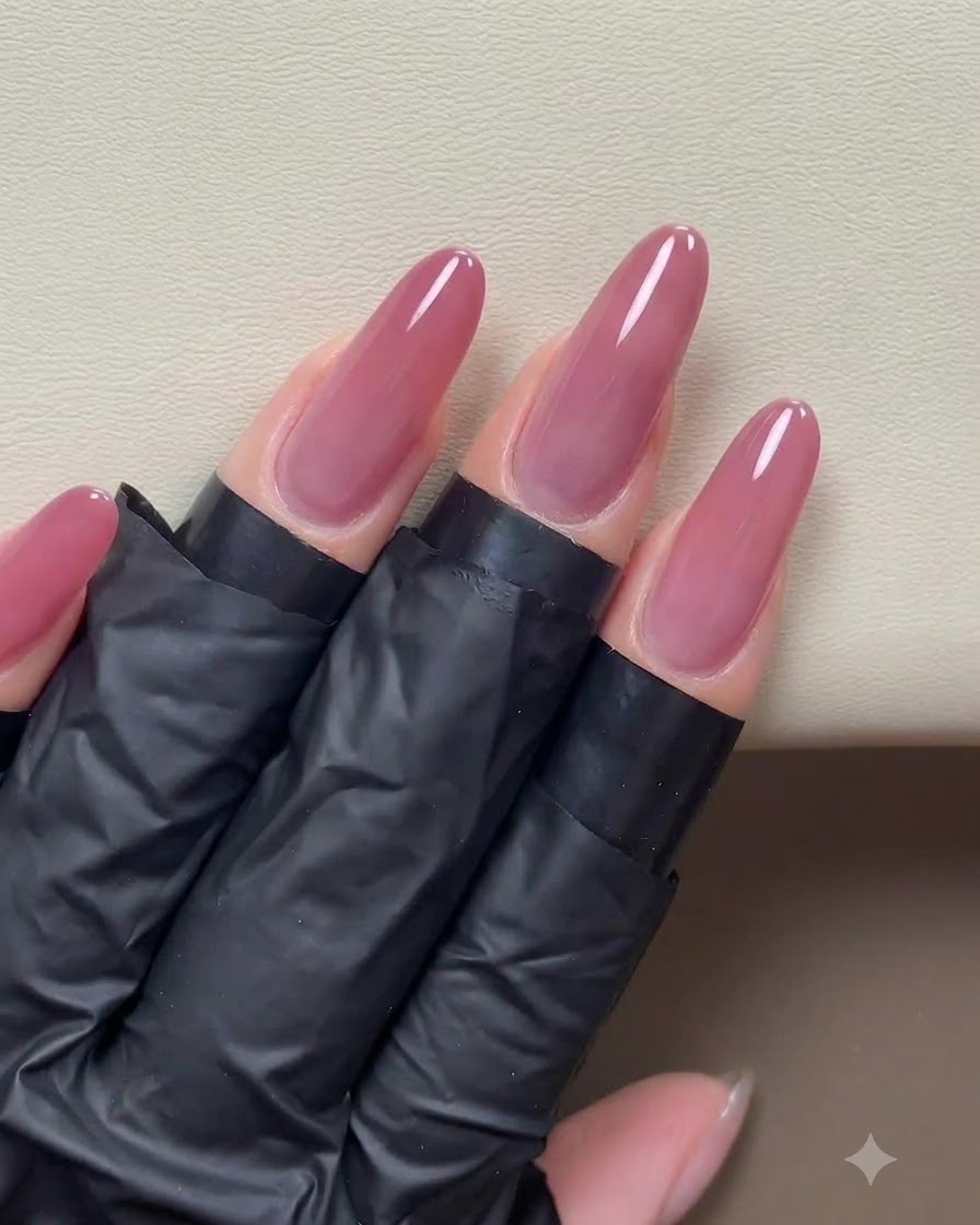 A completed application of pink-gold cat-eye gel evenly coating the surface of prepped long nails.