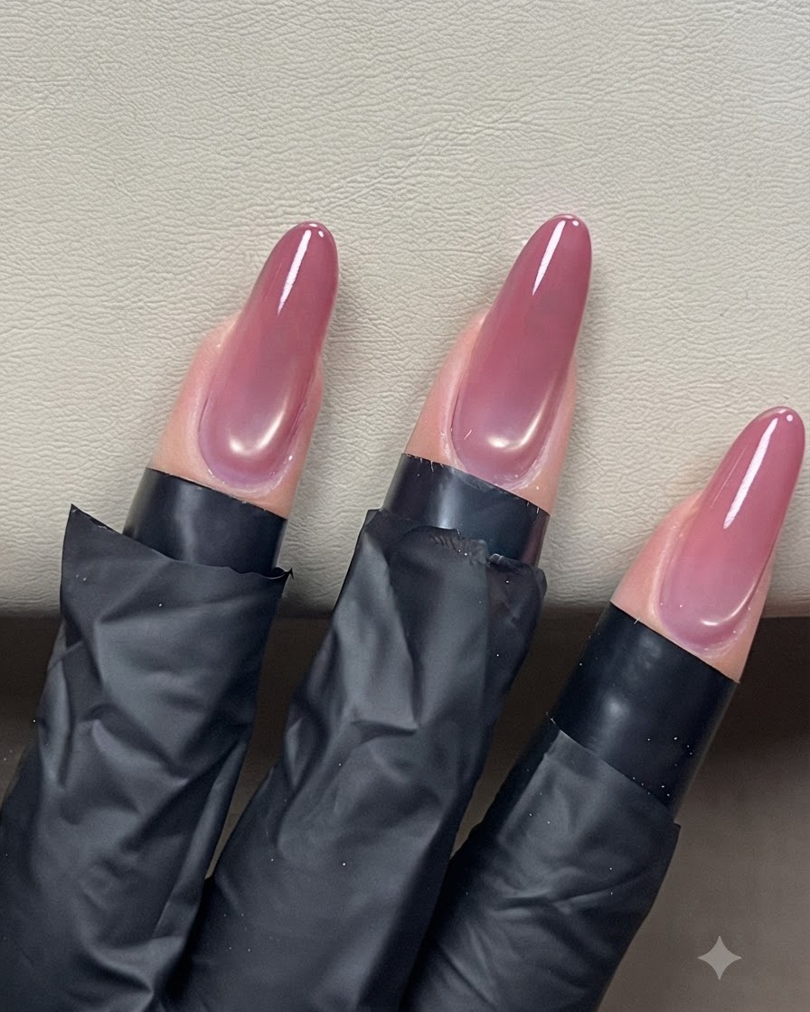 A nail brush gliding a clear top coat over almond-shaped cat-eye nails for a glossy finish.