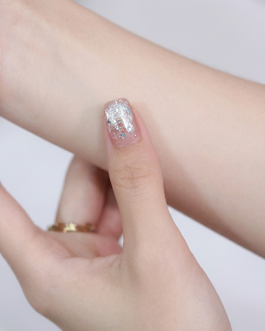 A round steel magnet held above a painted nail to move the cat-eye magnetic particles.