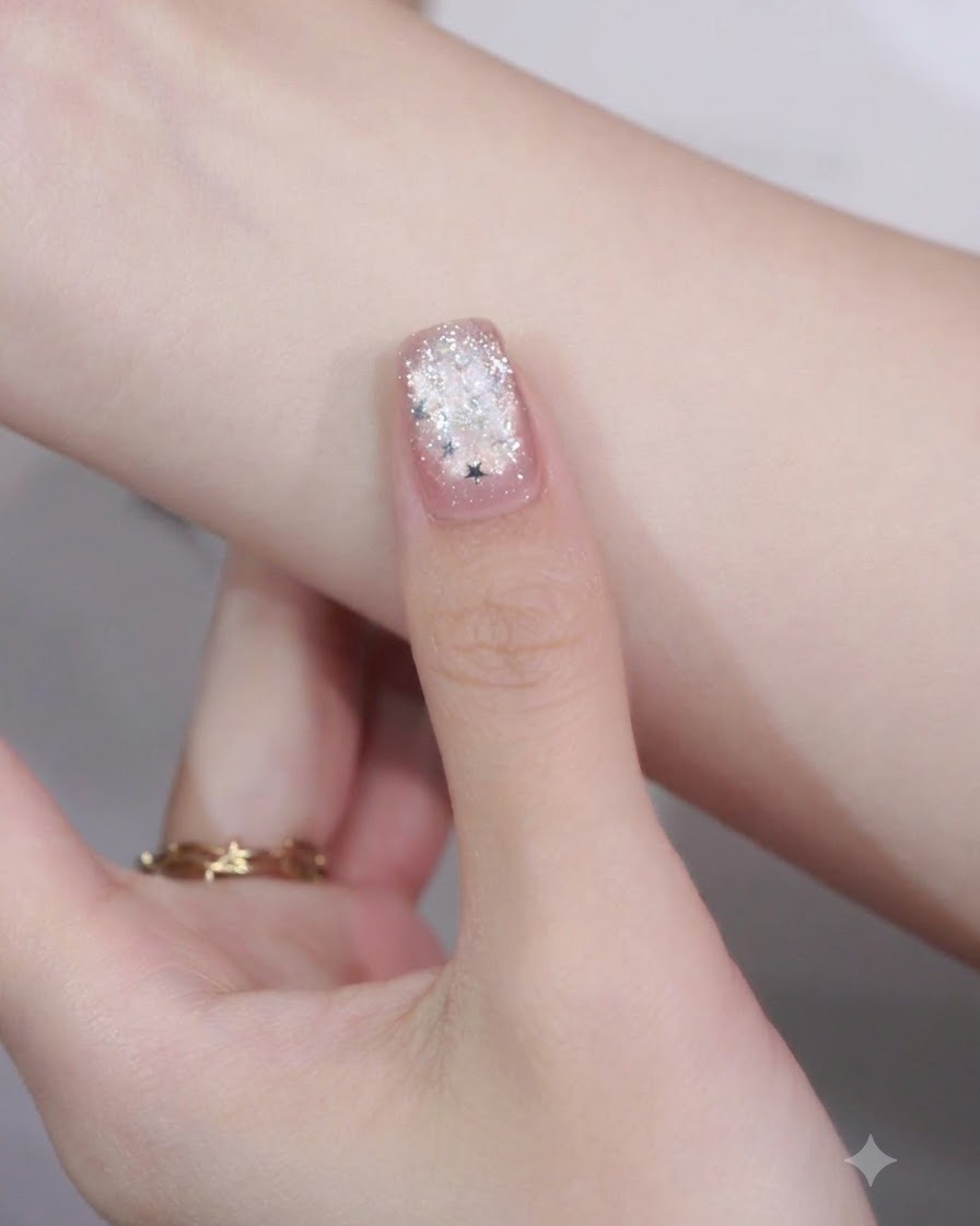 A close-up of a manicured nail with a star glitter piece placed on the tip over a fringe nail art detail.