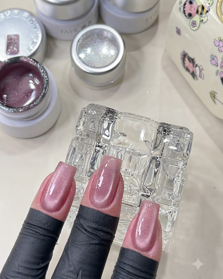 A hand showing cured pink cat-eye nails with a shimmering finish.