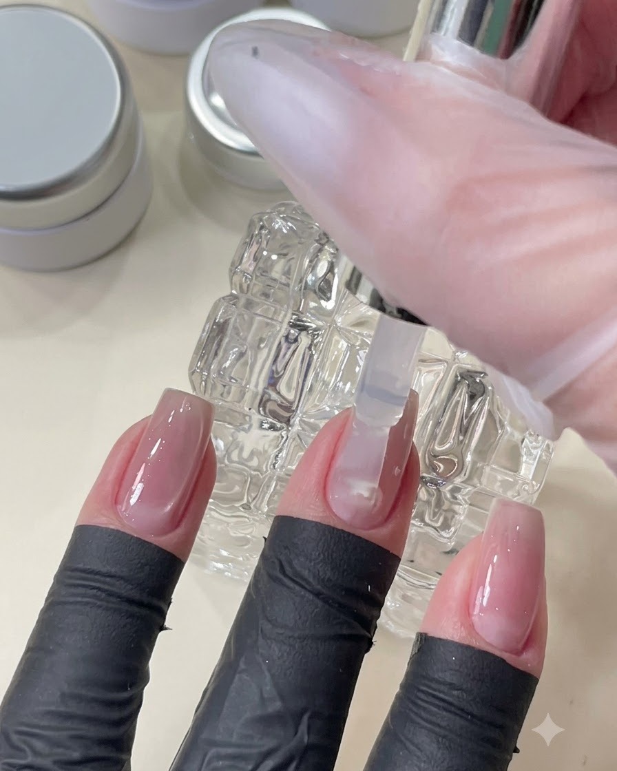 A brush applying a clear top coat gel to smooth and level the nail surface over embedded nail art.