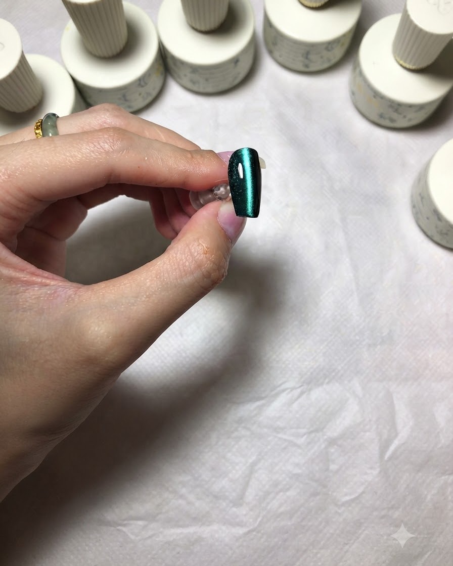 A finished green cat eye nail showing a sharp, centered line of bright light.