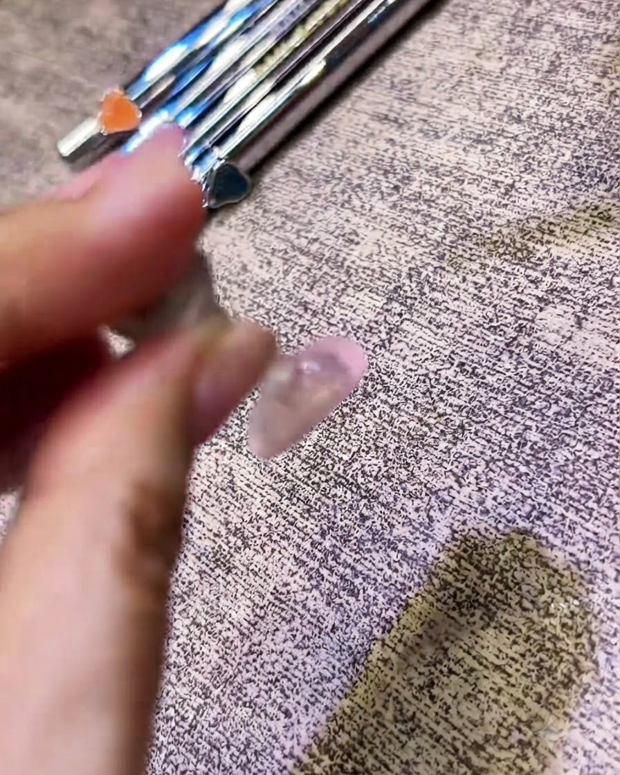 A brush applying a clear top coat over a chrome-finished nail.