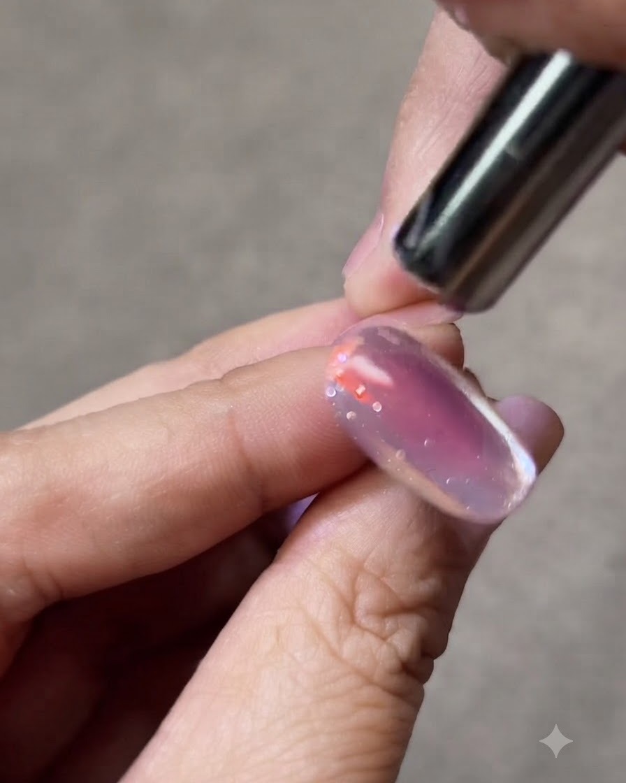 A small magnet held closely beside a cat-eye gel nail to shape the glowing light stripe.