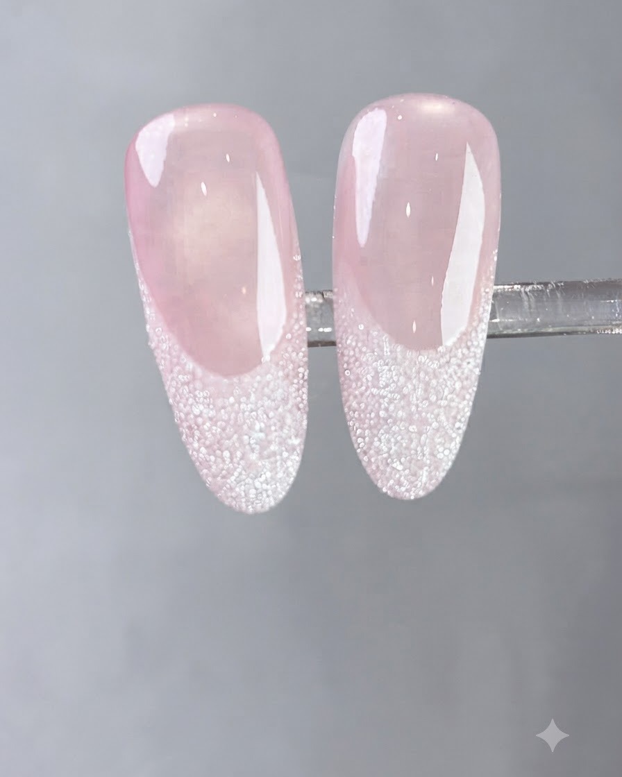 A brush applying a coat of flowing milky white gel onto a natural fingernail.