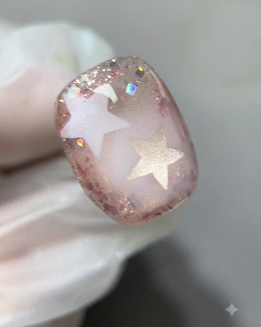A detailed close-up showing pink glitter gel being painted around the edges of the nail.