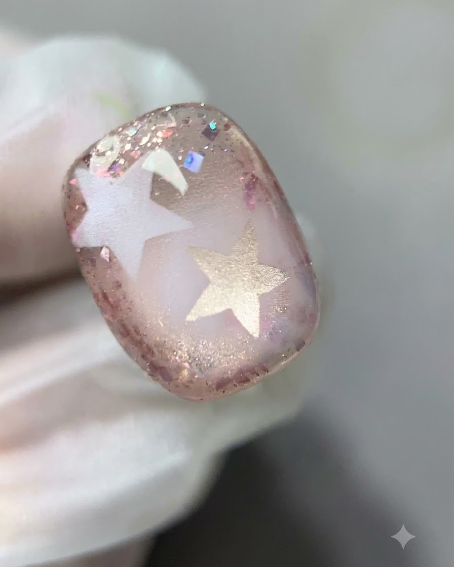 A brush gently feathering the inner boundary of the pink glitter gel on the nail.