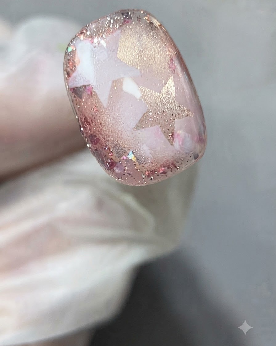 A pair of tweezers or gloved fingers gently peeling a star stencil away from the cured nail art.