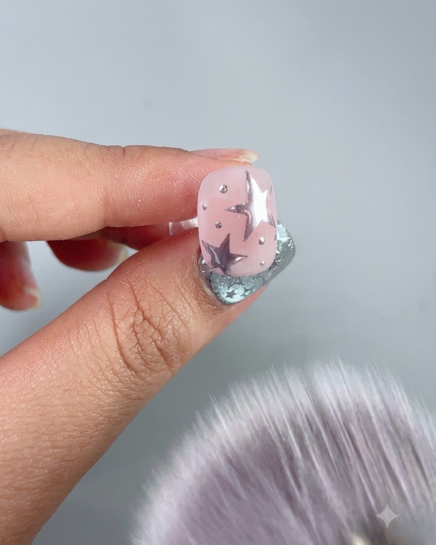 A soft dusting brush sweeping away excess powder from a decorated nail.