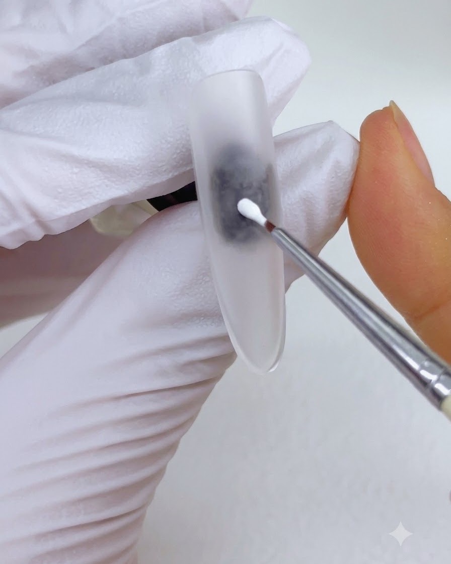 A fine detail brush placing a dot of white painting gel onto the center of a matte nail surface.