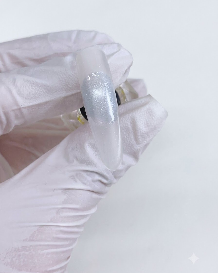 A finished cat eye gel bead on a nail after curing under a lamp.