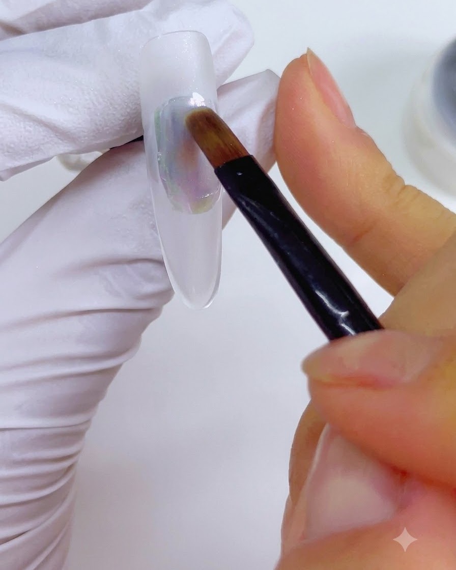 A detail brush dampened with nail cleanser being gently stroked across the multicolored ink application on the nail.