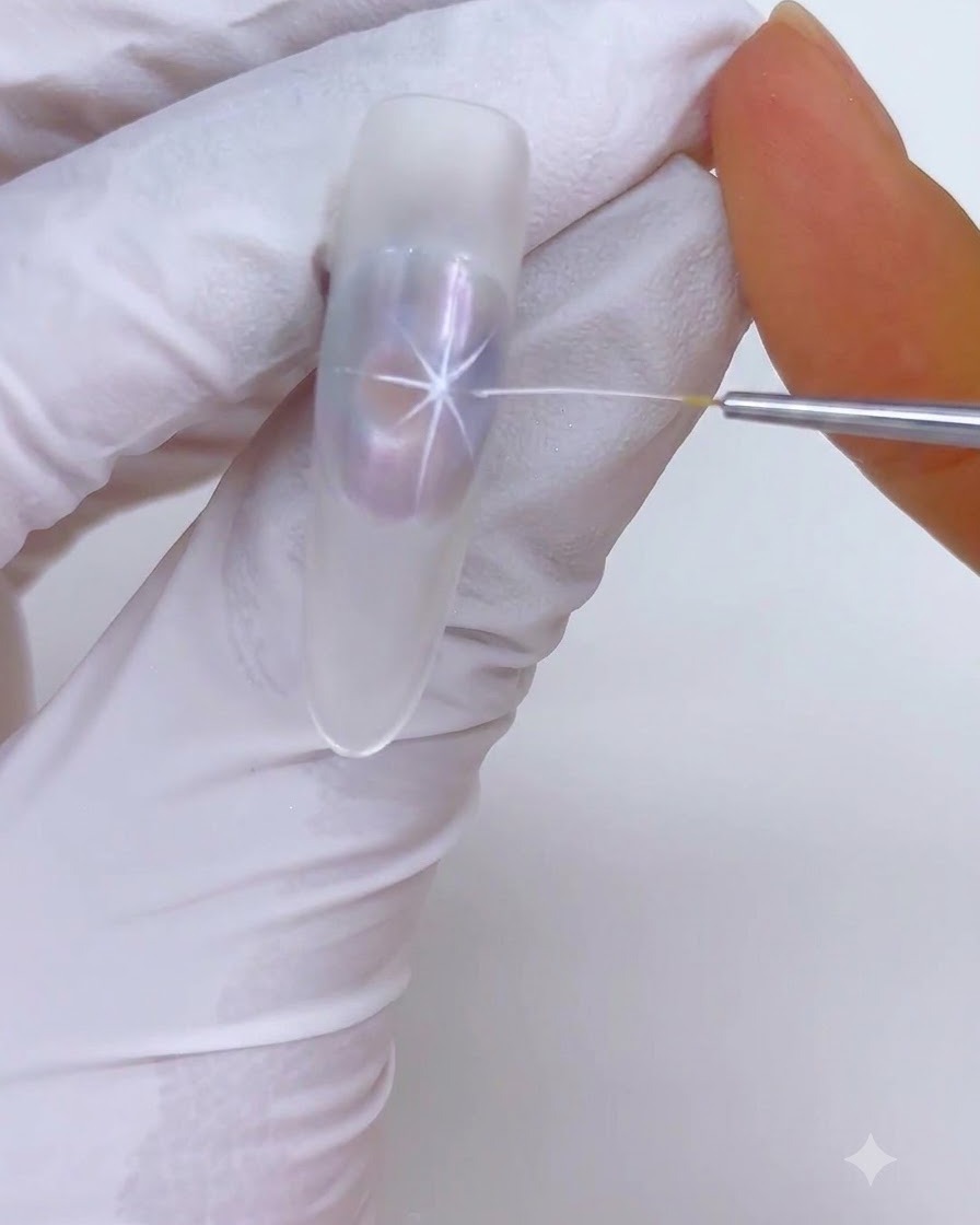 A fine liner brush drawing white starburst highlights over a translucent nail design.