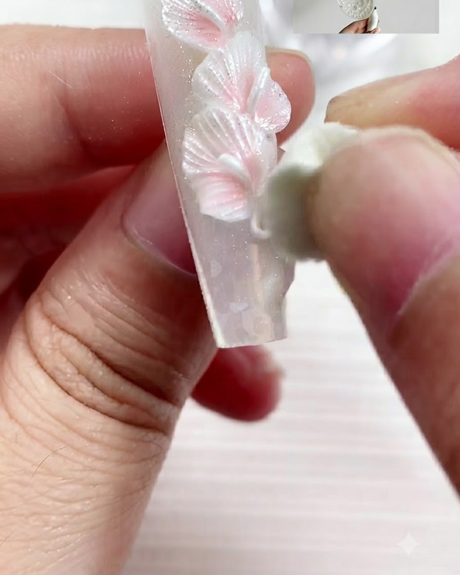 A sculpting tool pressing and shaping a piece of gel into a flattened calla lily petal.