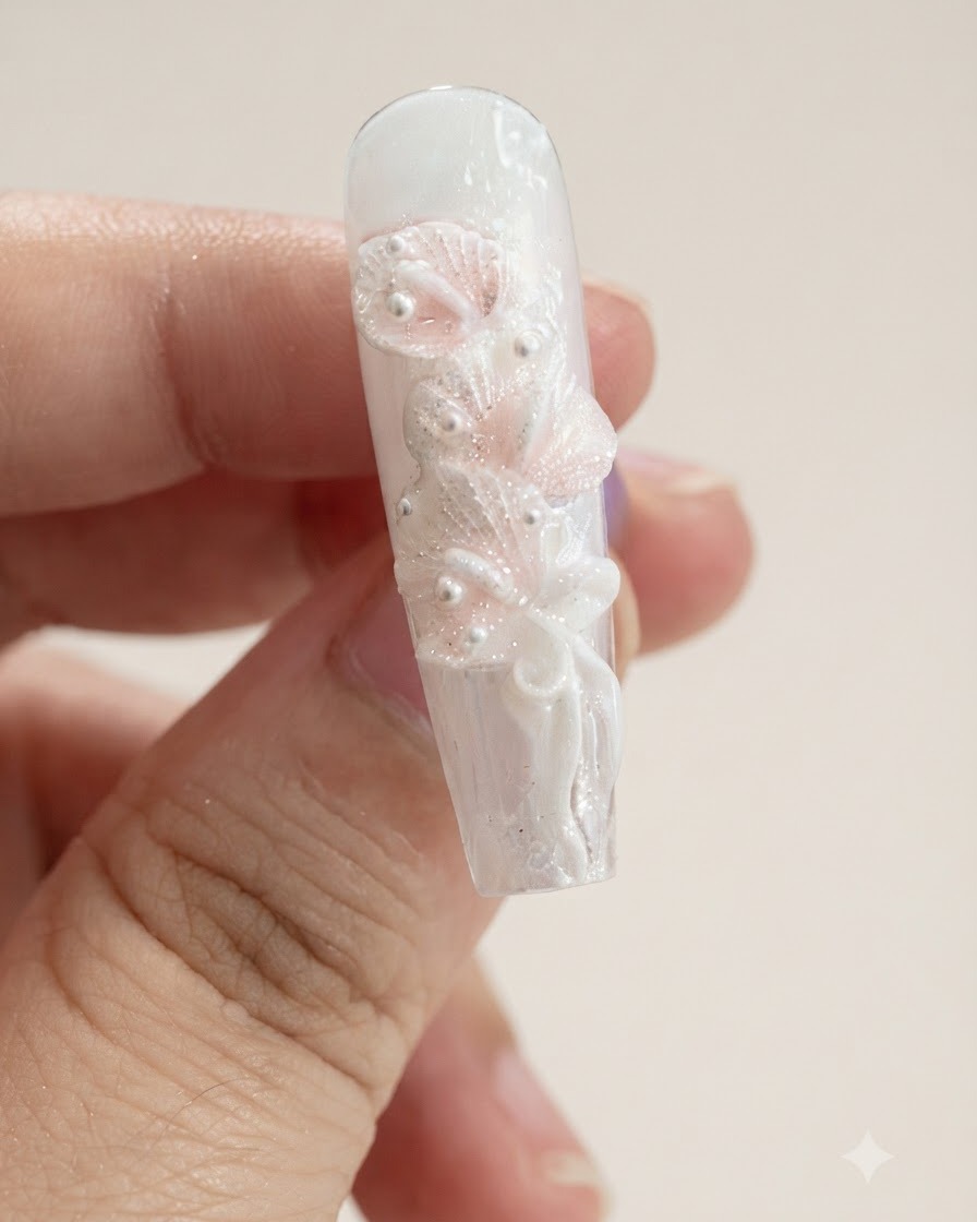A close-up view of a nail with multiple sculpted white calla lily petals and a ribbon bow.