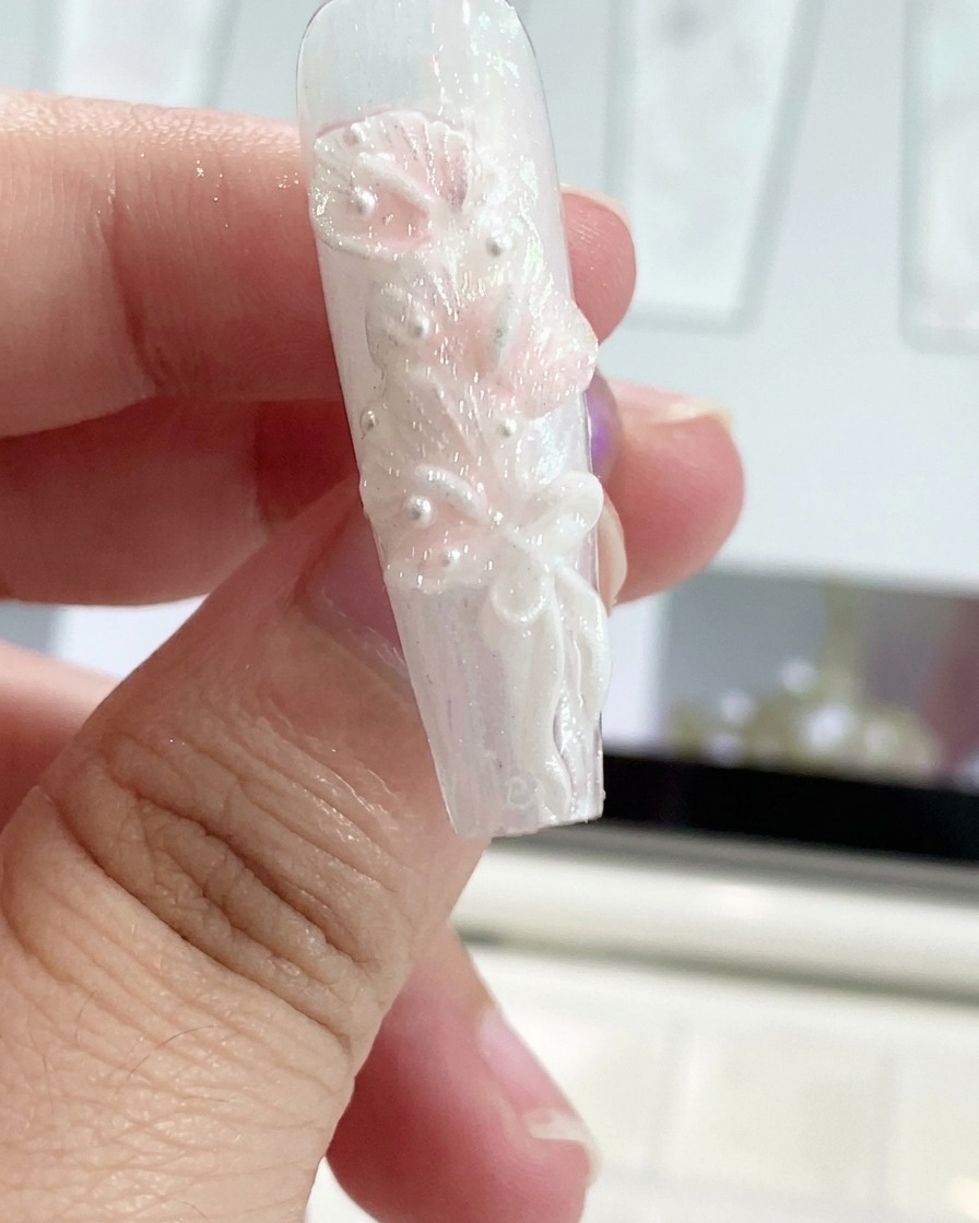 A silicone tool shaping a gel bow ribbon on a decorated fingernail.