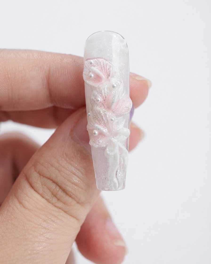 A makeup sponge dabbing light pink gel onto sculpted white calla lily petals.