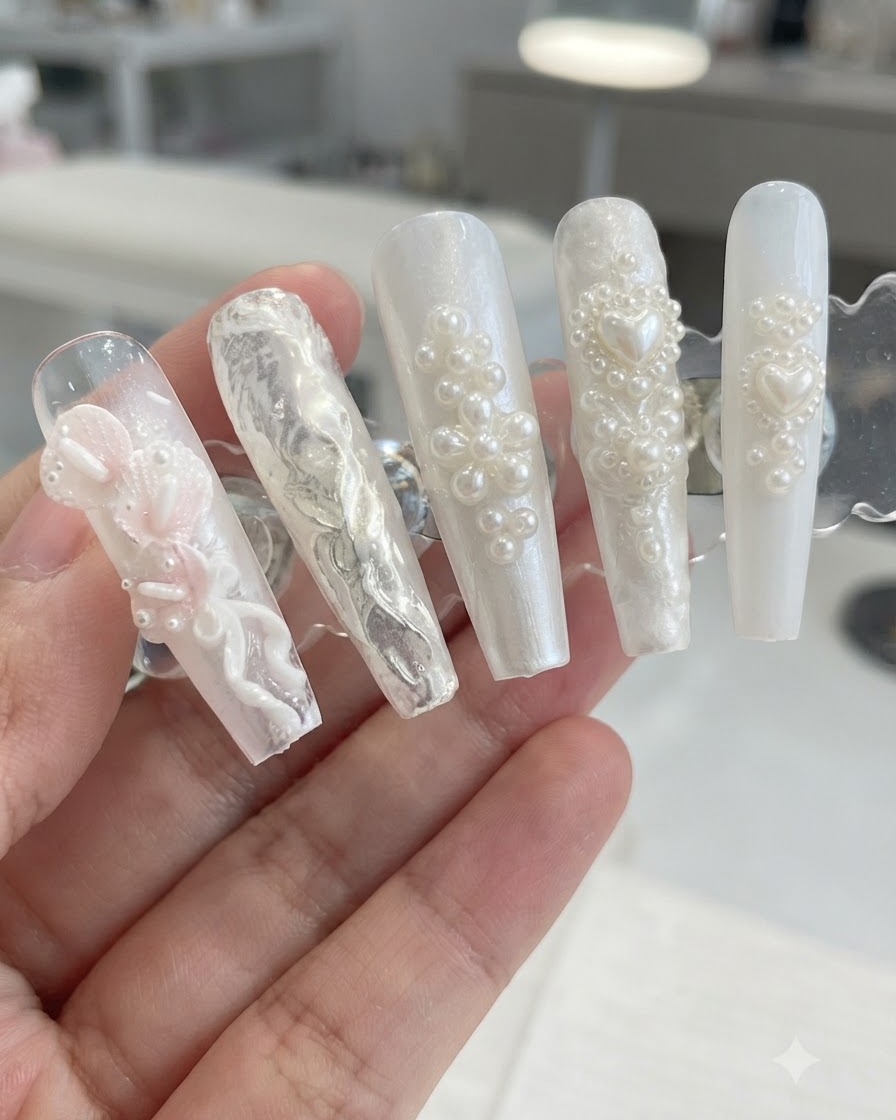 A display stand showcasing 3D pearl and floral nail designs after brushing away excess shimmer powder.