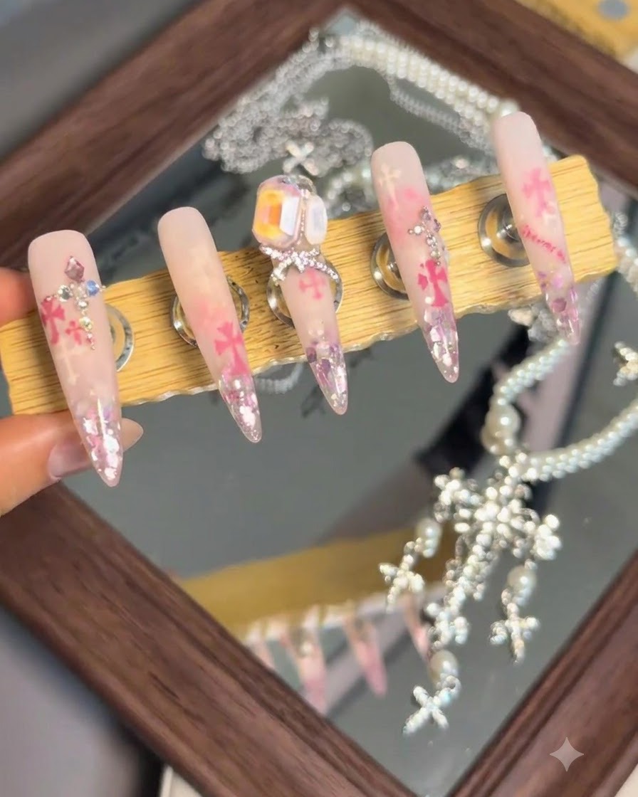 A display stand showing a set of finished nail art pieces featuring a prominent large crystal and bow charm on the center nail.