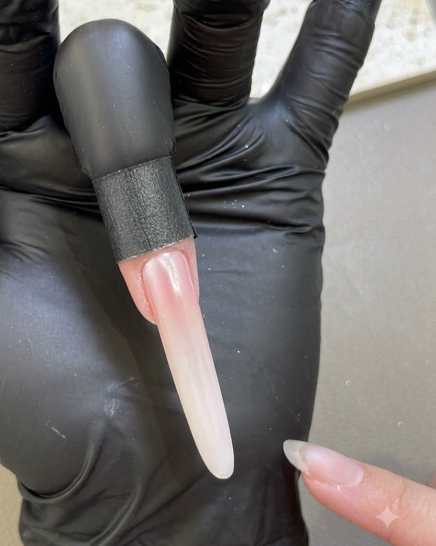 An extended nail showing a smooth, pearlescent finish after sealing with base gel along the edges.