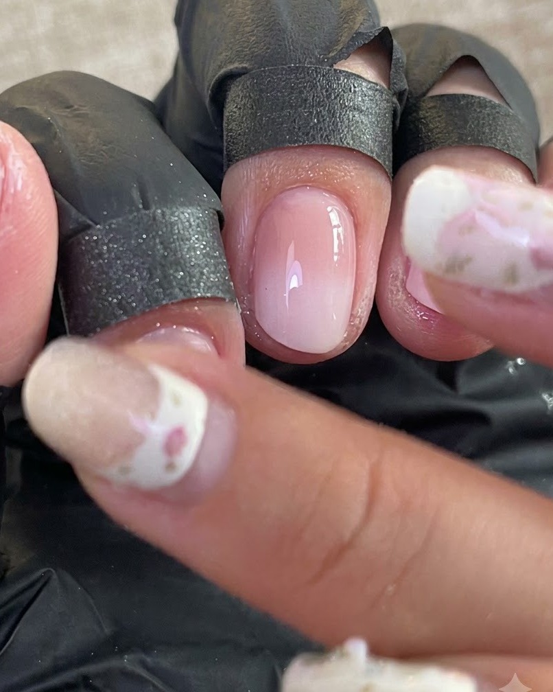 A close-up view of prepped nails with fingers protected by black finger cots during the chrome buffing process.