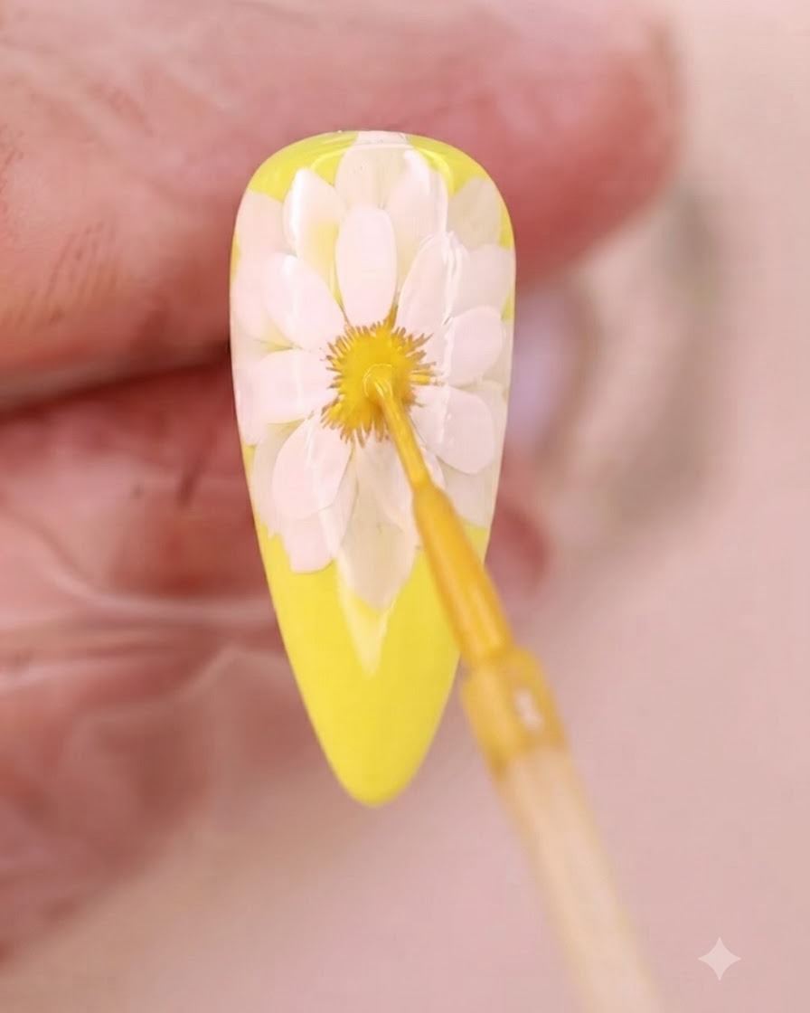 A fine brush applying yellow liquid to the blooming center of the flower.