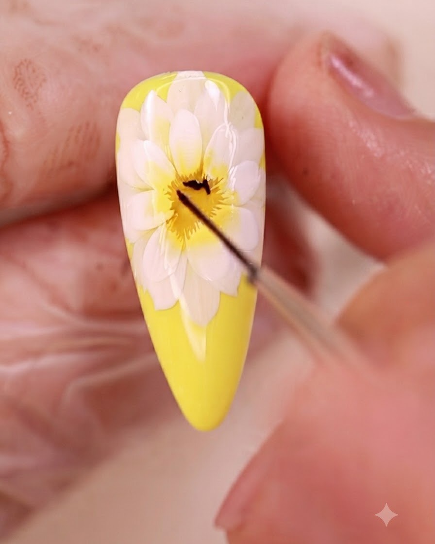 A fine liner brush drawing fine black lines in the center of the floral nail art.