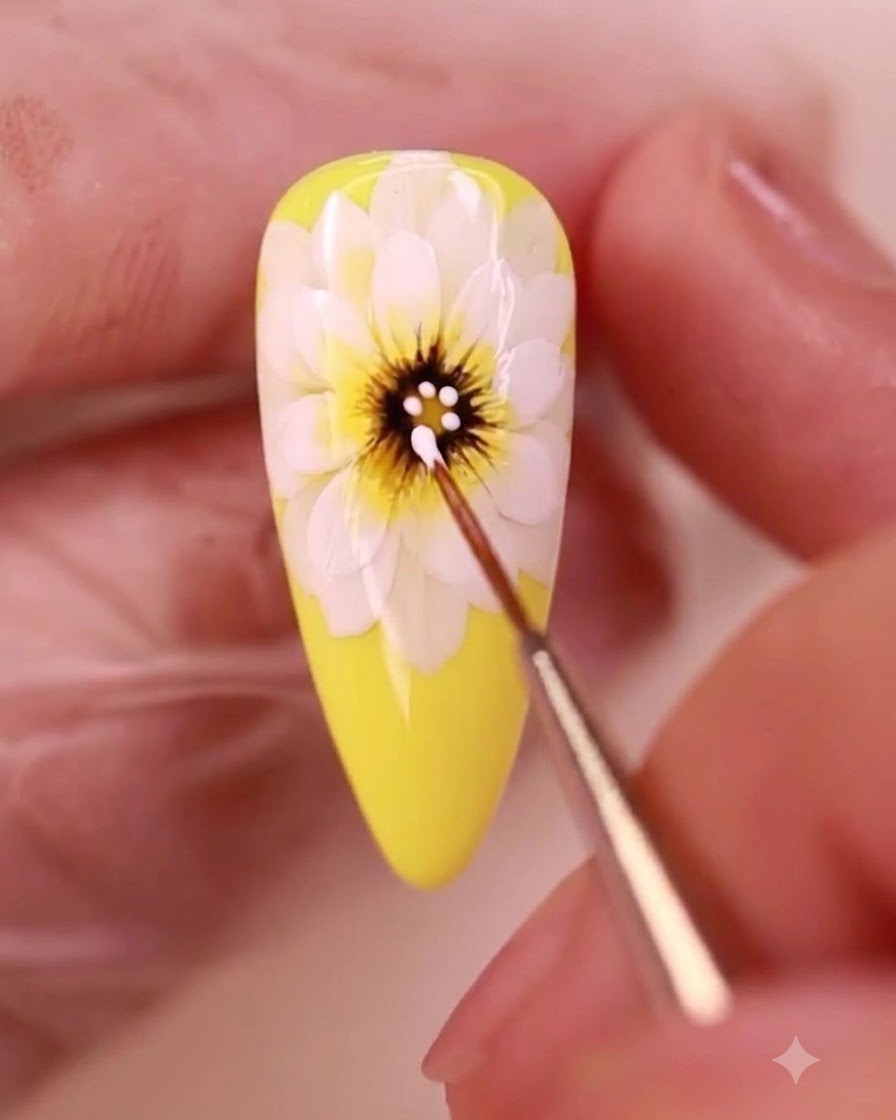 A detail brush applying white gel dots onto the dark center of a painted yellow daisy.