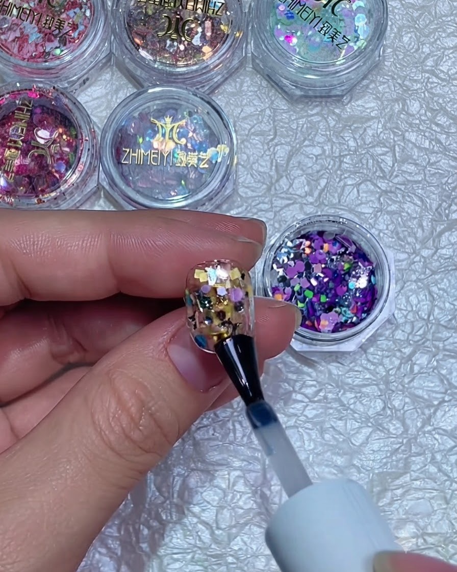 A nail buffer smoothing the surface of a cured glitter-encapsulated nail.