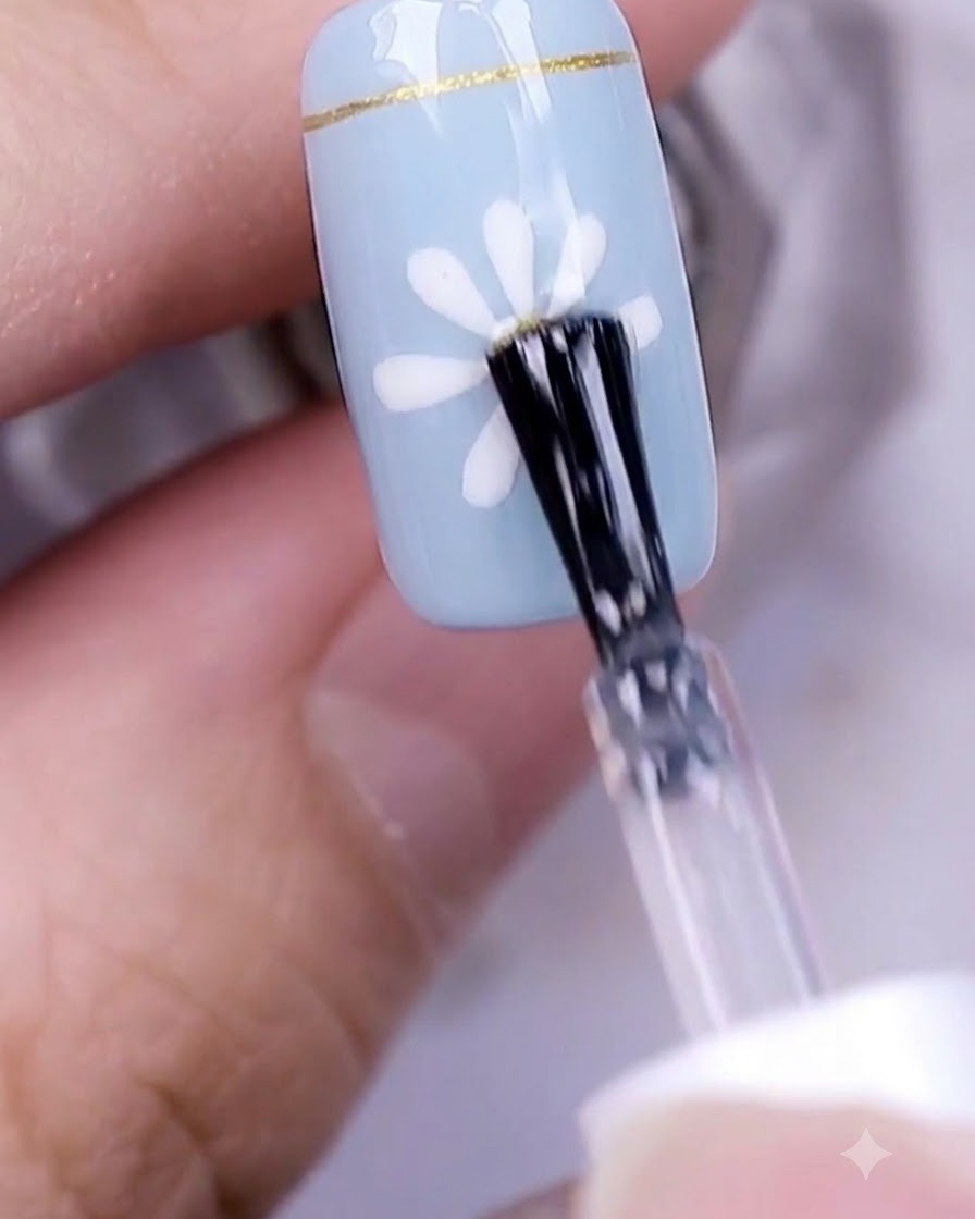 A hand with a finished daisy nail design curing underneath a professional UV nail lamp.