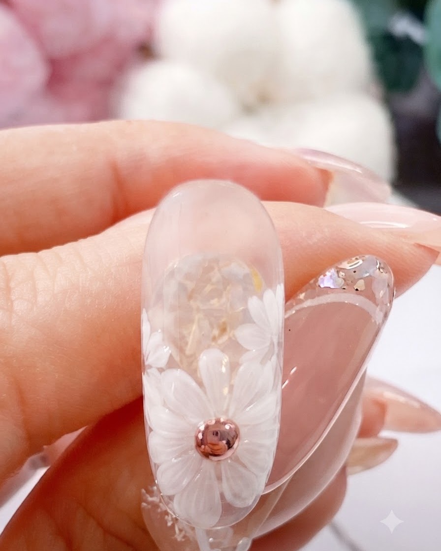 A fine brush placing a brown gel dot in the center of a painted white daisy.