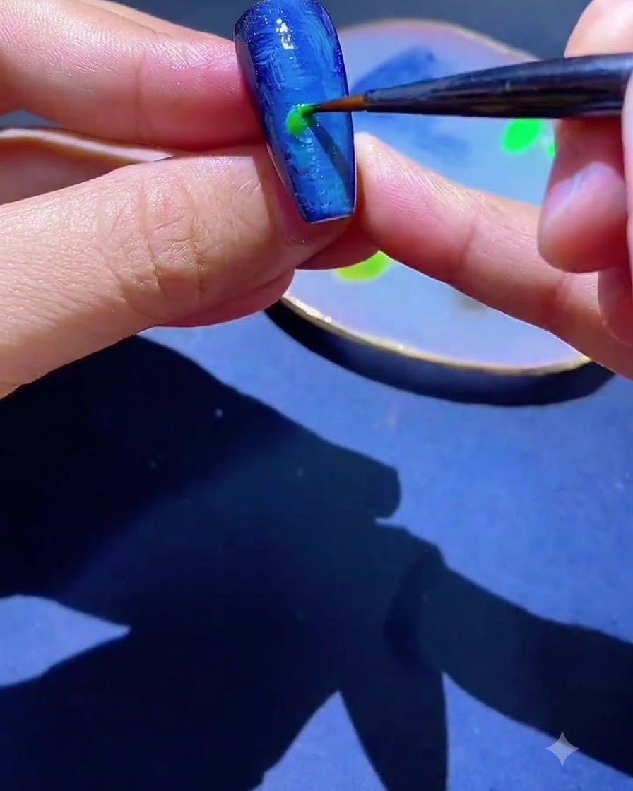 A fine liner brush applying a spot of green gel polish onto a blue textured nail.
