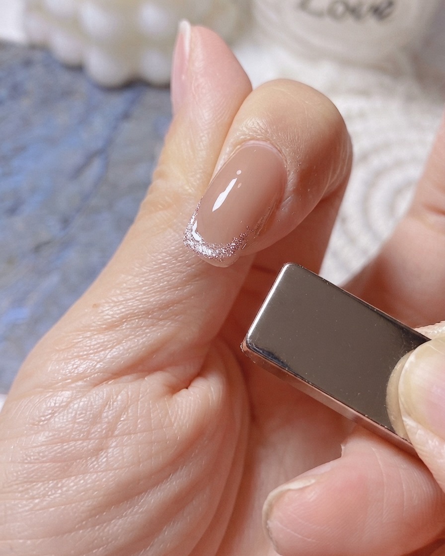 A magnet positioned on the right side of a finger to form a wide luminous band on a cat-eye French tip.