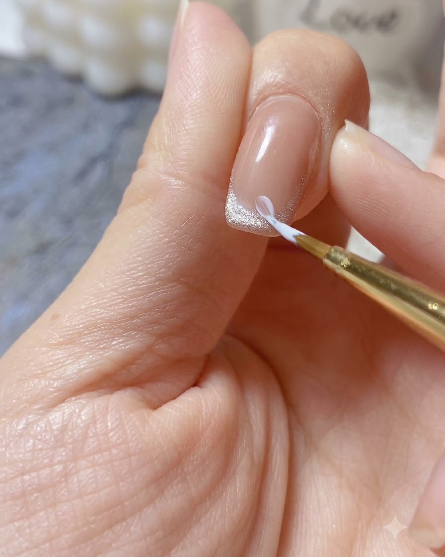 A fine brush applying a dollop of thick white relief gel to form a 3D daisy petal on a manicured nail tip.