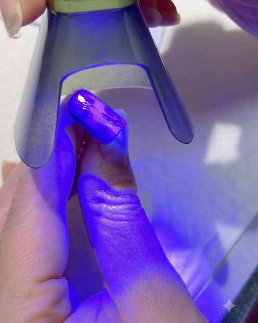 A purple UV lamp curing the light green leaf details on a painted nail.