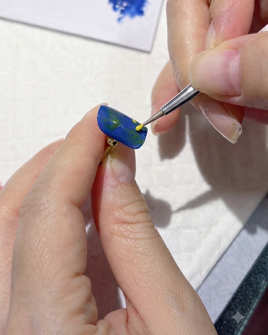 A fine detailing tool applying yellow dots to mark flower centers on a blue nail.