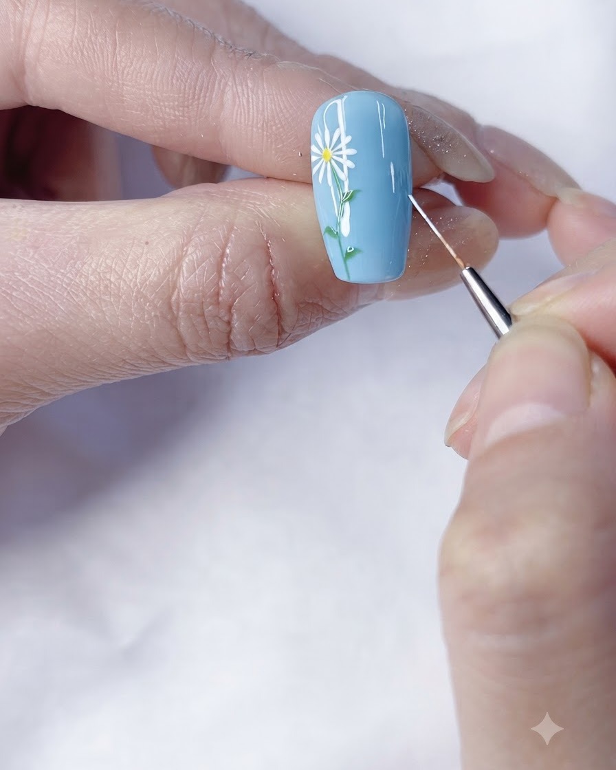 A close-up shot of painting more white petals around the center of the daisy on a blue background.