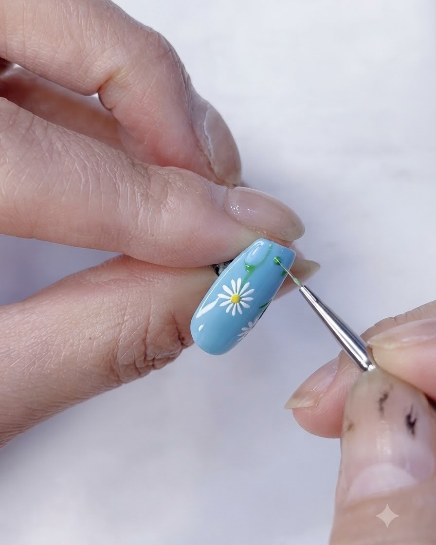A close-up view of a completed daisy floral nail art design on a light blue base.