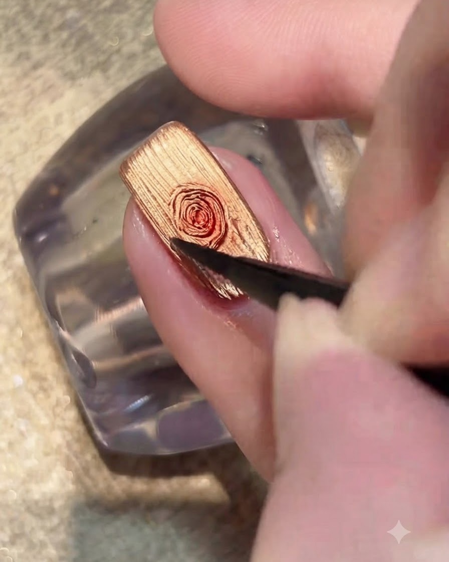 A brush applying a transparent coat of blooming gel over the gold cat-eye nail surface.