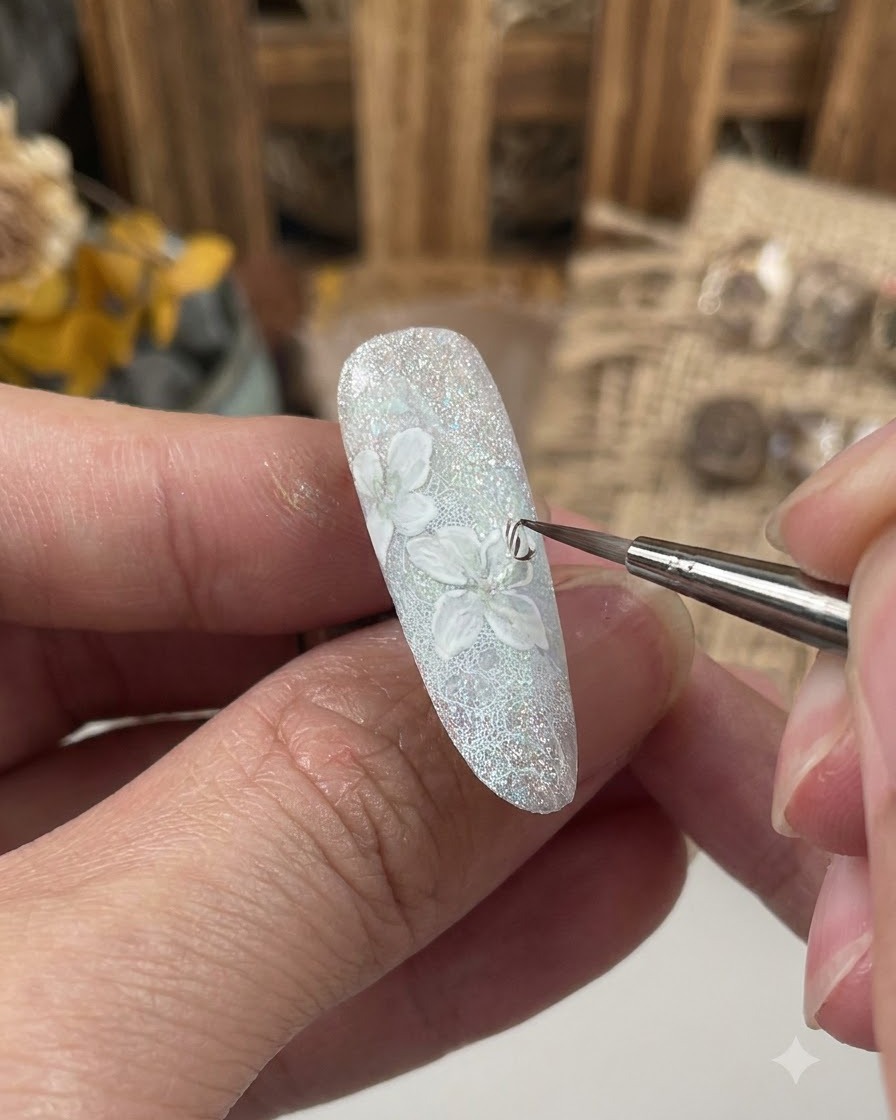 A fine brush applying a sealing gel layer over the detailed flower design on a decorated nail.