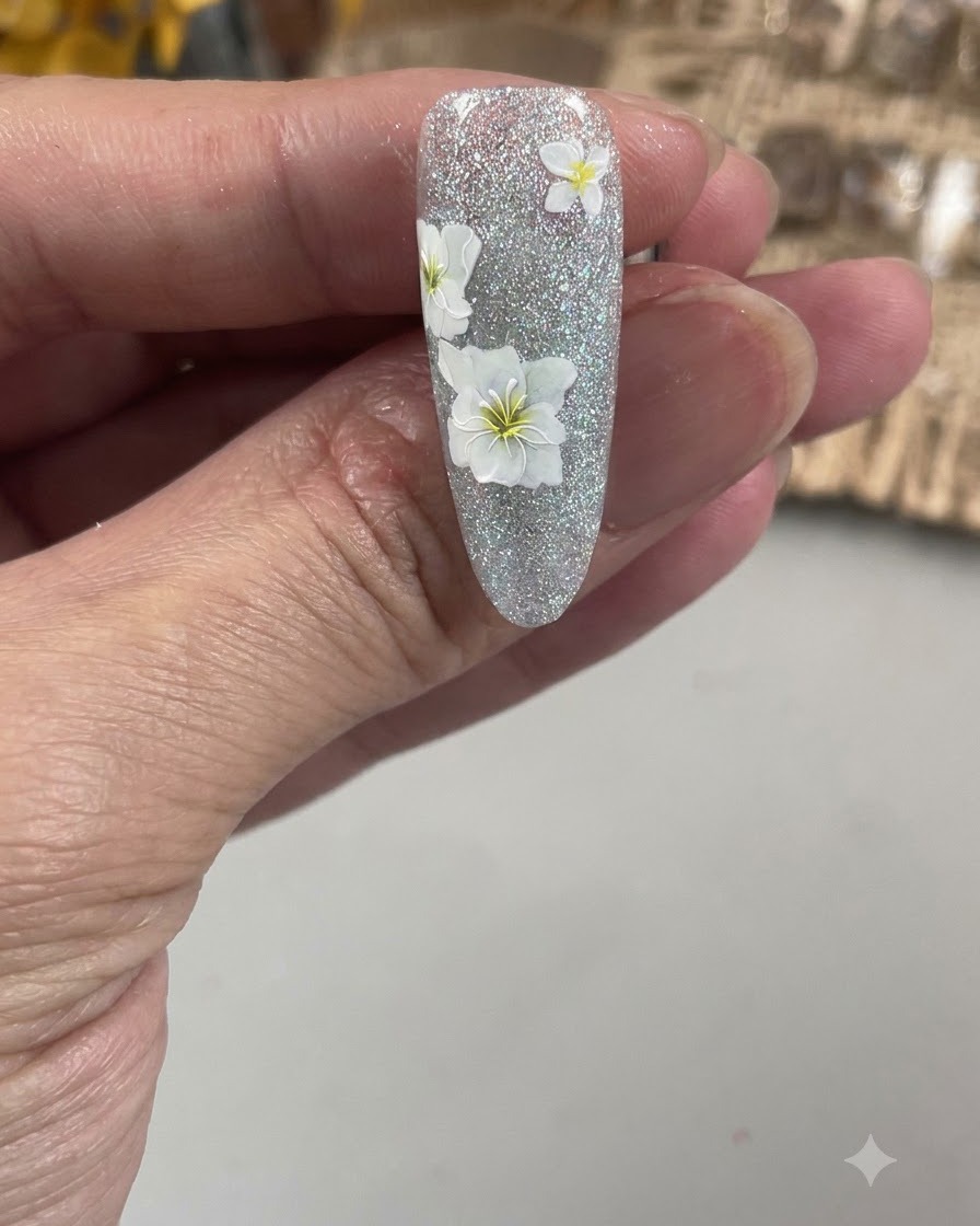 A close-up view of a fine nail art brush outlining the delicate petals of a white flower on a textured nail.