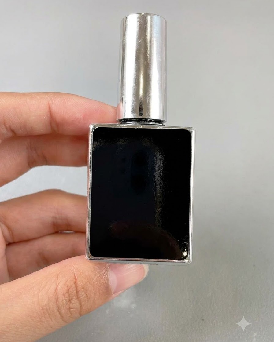 A small black rectangular bottle of nail gel polish being held by a hand against a neutral background.