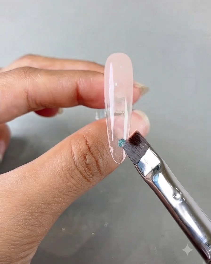 A nail brush applying a small piece of blue sequin onto a long clear practice nail.
