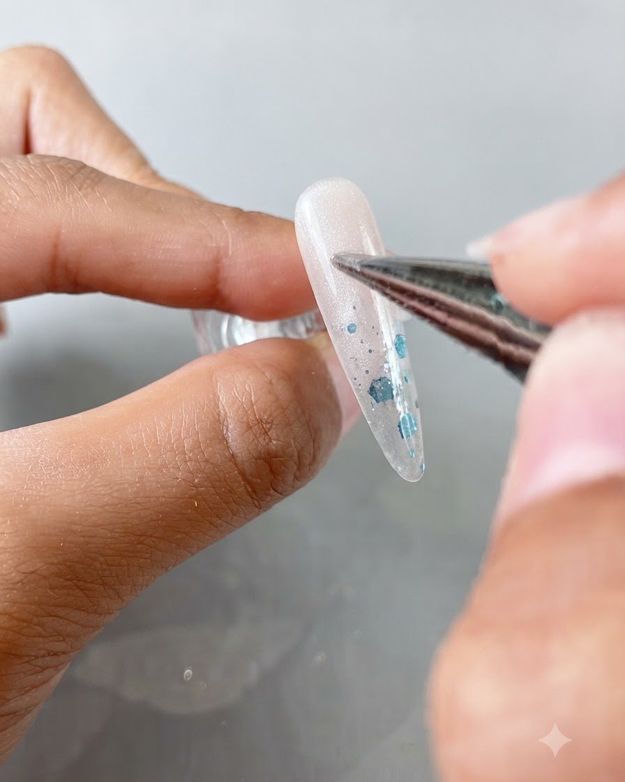 A precision brush applying clear cat eye gel onto an almond-shaped nail.