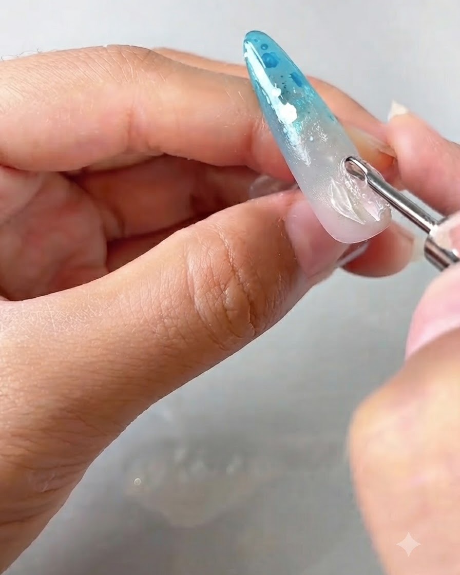 A detail tool placing and lifting the edges of a transparent petal gel onto a decorated nail.